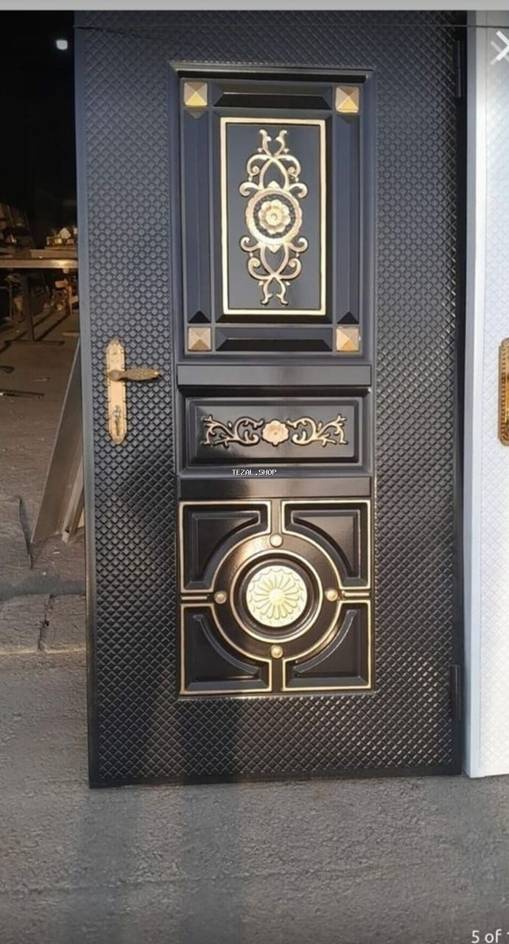 Qara rəngdə, üzərində qızılı naxışlar olan dəmir qapı. Qapının