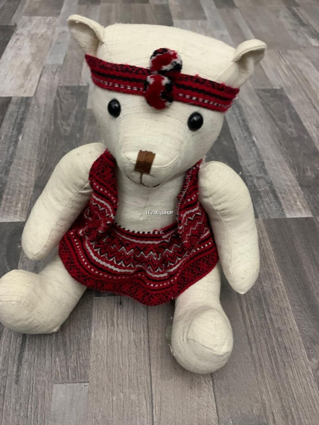 Ağ rəngli parça ayı oyuncağı, qırmızı və qara rənglərdə naxışlı bant