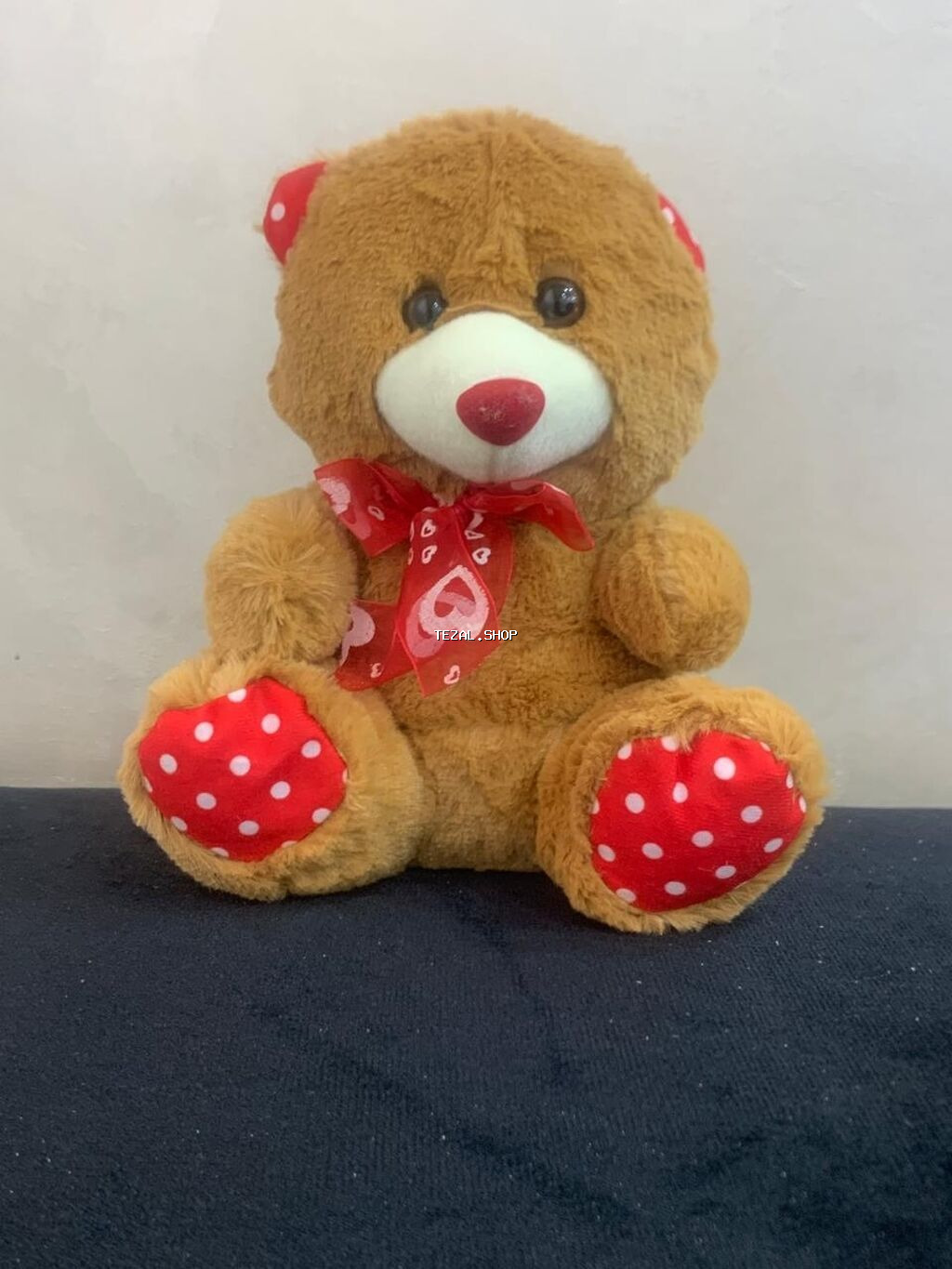 Qəhvəyi rəngli, yumşaq oyuncaq ayı. Ayının əlləri və qulaqları qırmızı