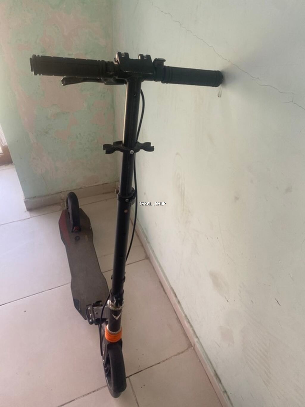 Qara rəngdə, qatlana bilən skuter. Bu skuter, şəhər daxilində səyahət